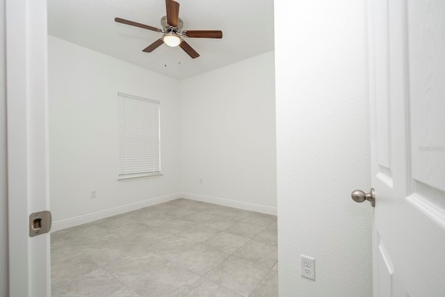 spare room featuring a ceiling fan and baseboards