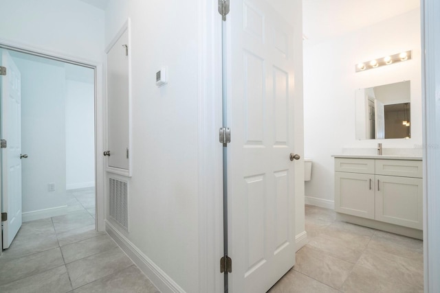 hallway with light tile patterned floors, visible vents, and baseboards