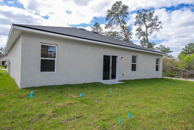 back of house with a yard and stucco siding