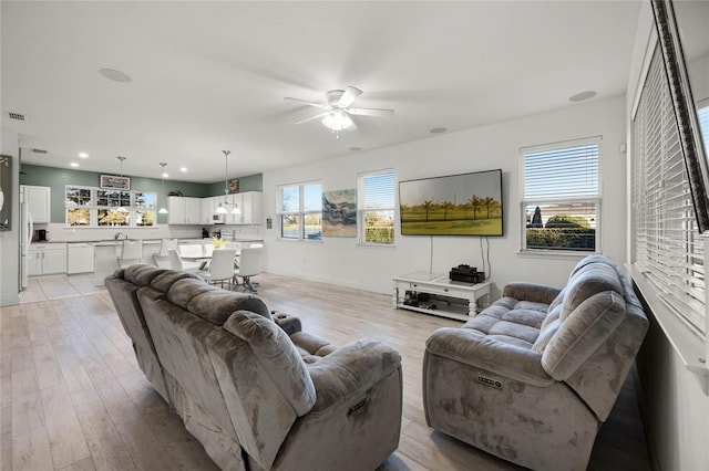 living area with light wood finished floors, visible vents, recessed lighting, and a ceiling fan