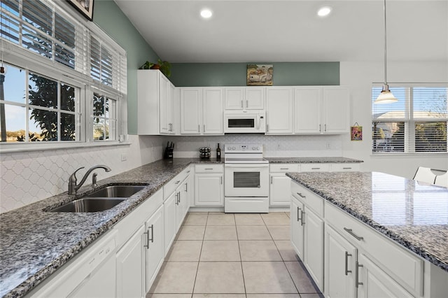 kitchen with a sink, stone countertops, white appliances, white cabinets, and light tile patterned floors