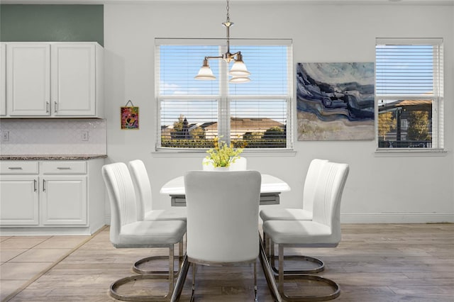 dining area featuring a chandelier, light wood-style flooring, and baseboards