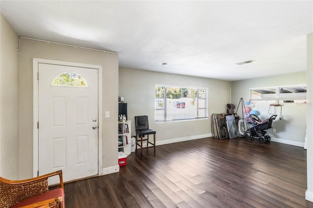 entrance foyer with a textured ceiling, wood finished floors, visible vents, and baseboards