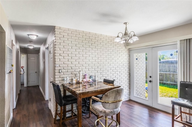 dining space featuring wood finished floors, french doors, a healthy amount of sunlight, and brick wall