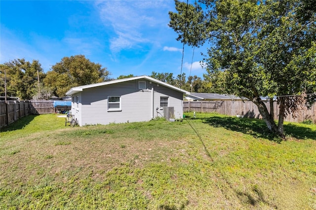 view of side of home featuring a fenced backyard, cooling unit, and a yard