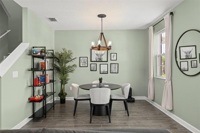 dining area featuring a notable chandelier, baseboards, visible vents, and wood tiled floor