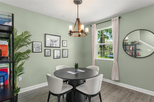 dining area featuring an inviting chandelier, baseboards, and wood finished floors