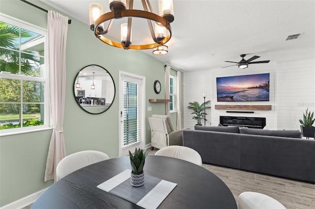 dining area featuring a wealth of natural light, visible vents, a fireplace, and wood finished floors