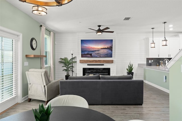 living area featuring visible vents, plenty of natural light, a fireplace, and light wood-type flooring