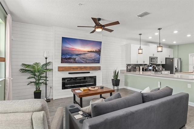 living area featuring visible vents, recessed lighting, a fireplace, and wood finished floors