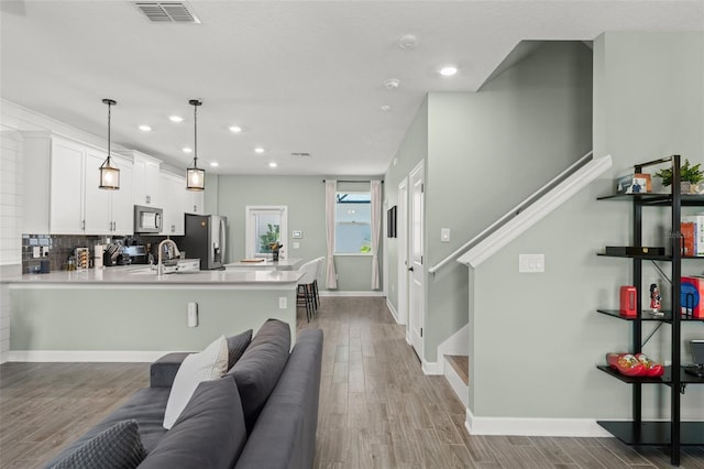 living room featuring light wood-type flooring, visible vents, and baseboards