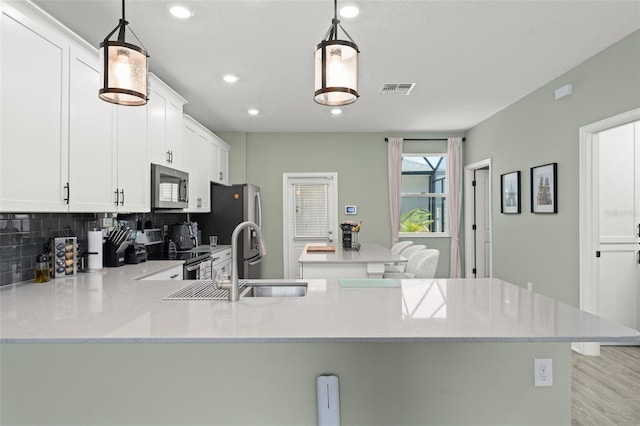 kitchen featuring visible vents, a sink, appliances with stainless steel finishes, white cabinetry, and tasteful backsplash