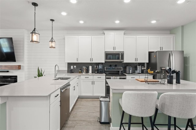 kitchen with appliances with stainless steel finishes, a breakfast bar area, light countertops, and a sink