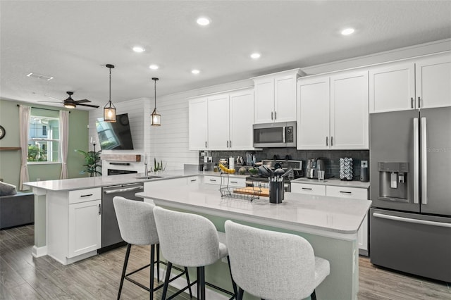 kitchen featuring light wood-style flooring, a center island, stainless steel appliances, a peninsula, and decorative backsplash