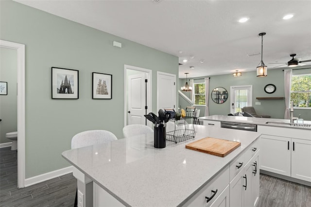 kitchen with a sink, plenty of natural light, a center island, white cabinetry, and hanging light fixtures