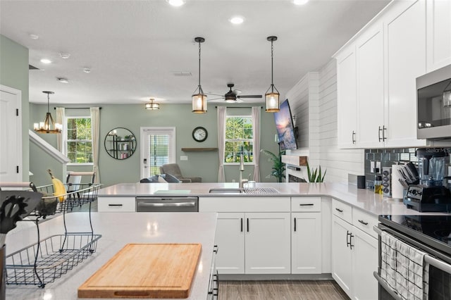 kitchen featuring a sink, tasteful backsplash, stainless steel appliances, a peninsula, and light countertops