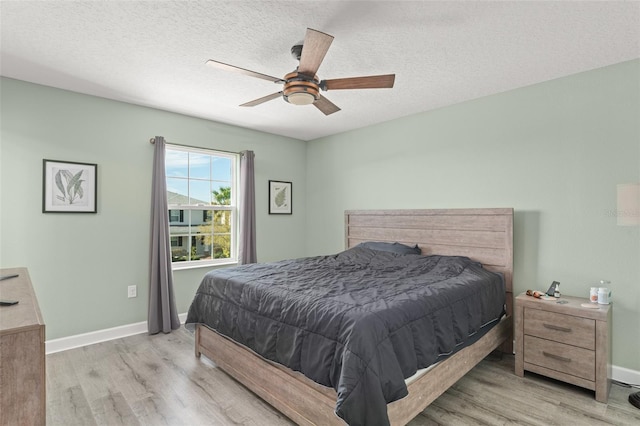 bedroom featuring wood finished floors, baseboards, and a textured ceiling