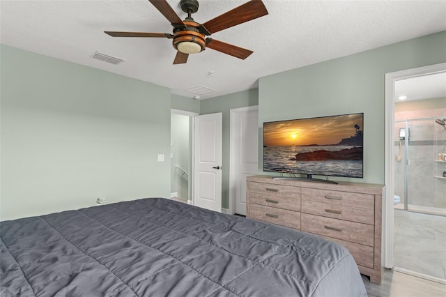 bedroom with visible vents, a textured ceiling, ensuite bathroom, and a ceiling fan