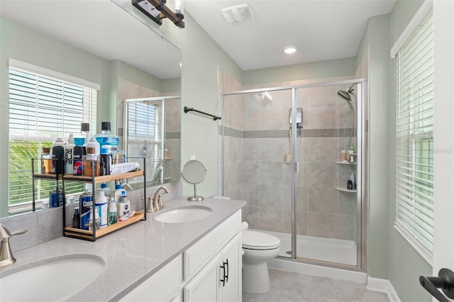 bathroom with a sink, a stall shower, and double vanity