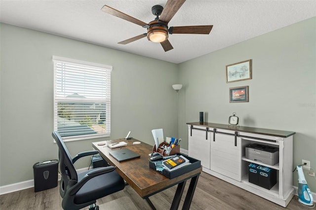 office space featuring baseboards, a textured ceiling, a ceiling fan, and wood finished floors