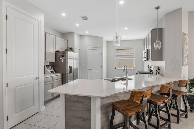 kitchen featuring visible vents, a peninsula, light tile patterned flooring, stainless steel appliances, and a sink