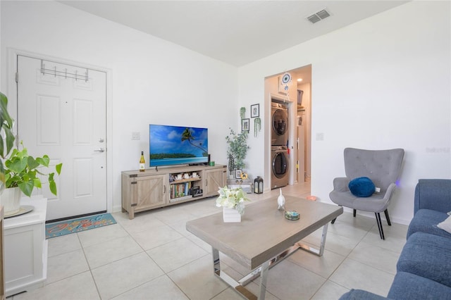 living area featuring light tile patterned floors, visible vents, and stacked washer / dryer