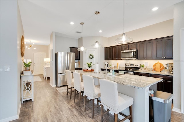 kitchen featuring a breakfast bar, light wood-style flooring, a sink, stainless steel appliances, and dark brown cabinets