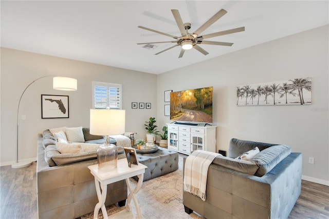 living room featuring a ceiling fan, wood finished floors, visible vents, and baseboards