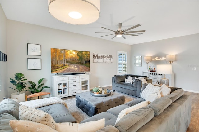 living room with ceiling fan, visible vents, baseboards, and wood finished floors