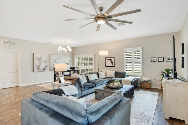 living area with visible vents, a healthy amount of sunlight, and ceiling fan with notable chandelier