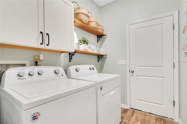 clothes washing area featuring washing machine and clothes dryer, cabinet space, and light wood-style floors