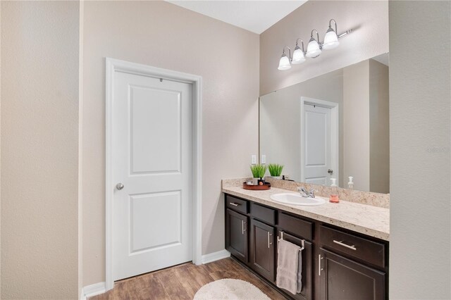 bathroom featuring vanity, wood finished floors, and baseboards