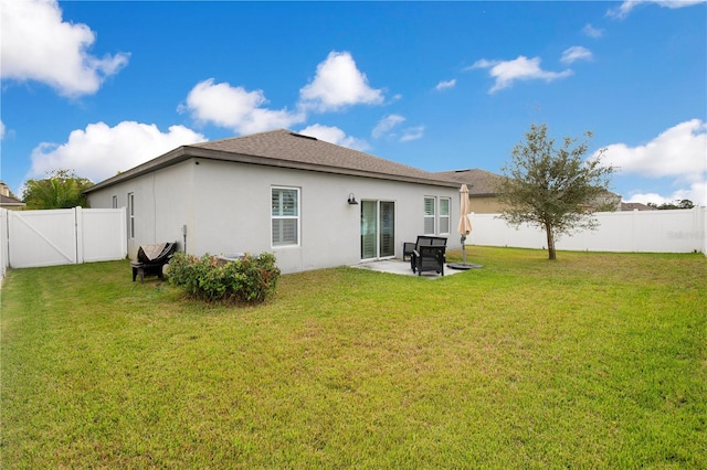 rear view of property with a patio, a gate, a yard, a fenced backyard, and stucco siding