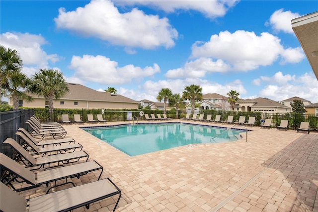 pool with a patio area, a residential view, and fence