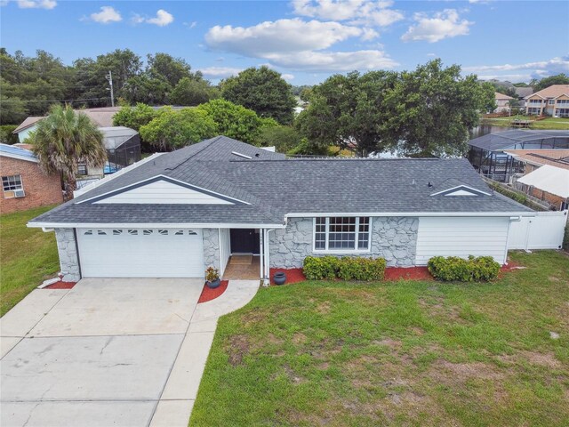 ranch-style home featuring a front yard, roof with shingles, driveway, stone siding, and an attached garage