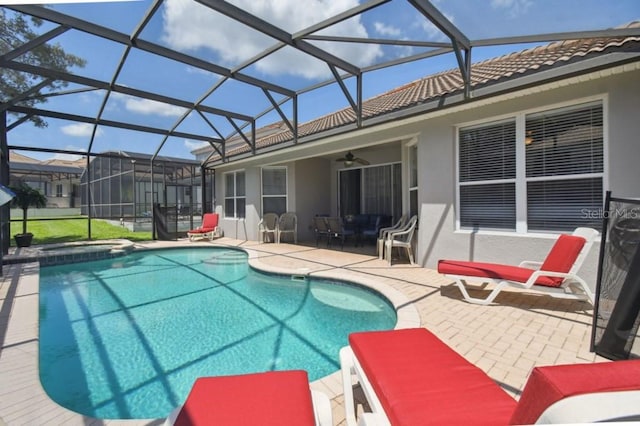 view of pool featuring glass enclosure, a pool with connected hot tub, a ceiling fan, and a patio