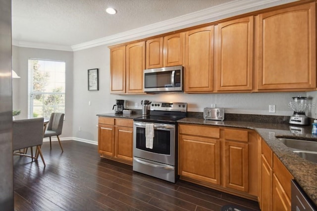 kitchen featuring crown molding, dark stone counters, appliances with stainless steel finishes, dark wood-style floors, and a textured ceiling