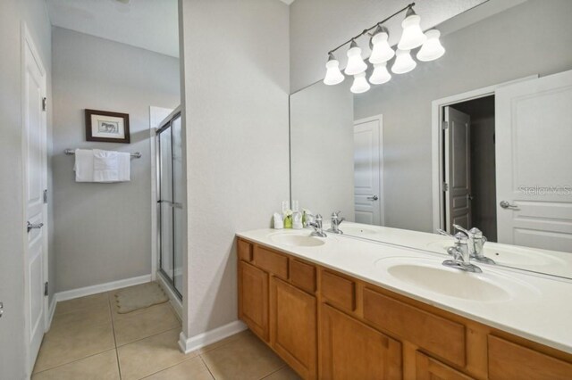 bathroom with a sink, double vanity, a shower stall, and tile patterned flooring