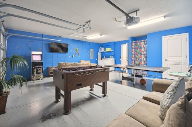 game room featuring a garage, a textured ceiling, concrete floors, and concrete block wall