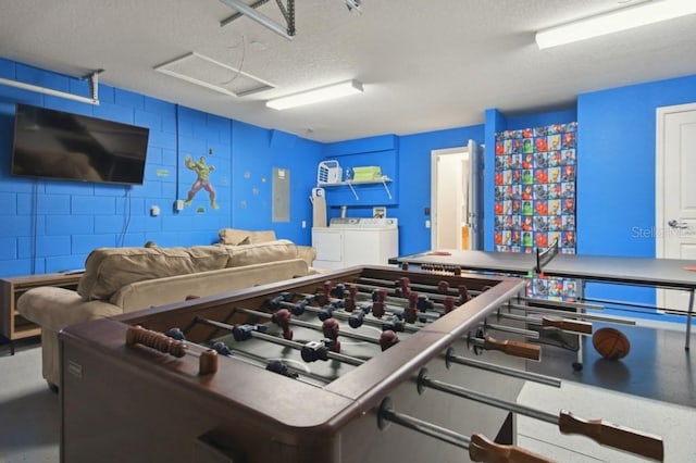 rec room featuring washer and dryer, a textured ceiling, and concrete block wall