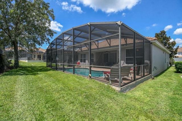 rear view of house with a patio, a yard, an outdoor pool, stucco siding, and a lanai