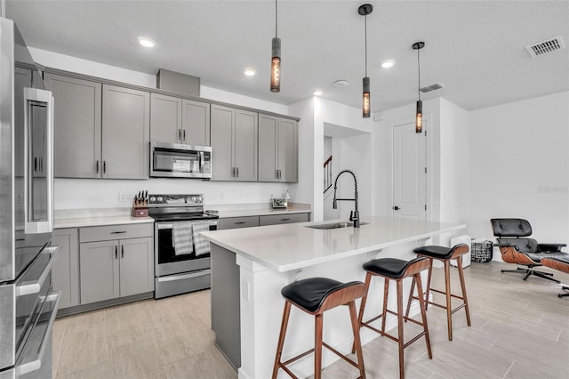 kitchen with visible vents, gray cabinets, appliances with stainless steel finishes, and a sink