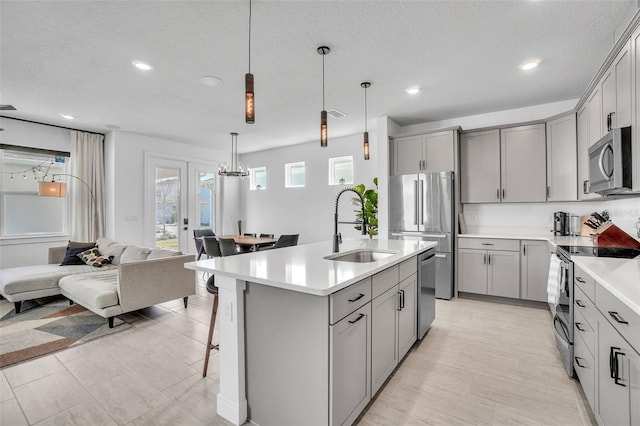 kitchen featuring open floor plan, gray cabinets, appliances with stainless steel finishes, and a sink