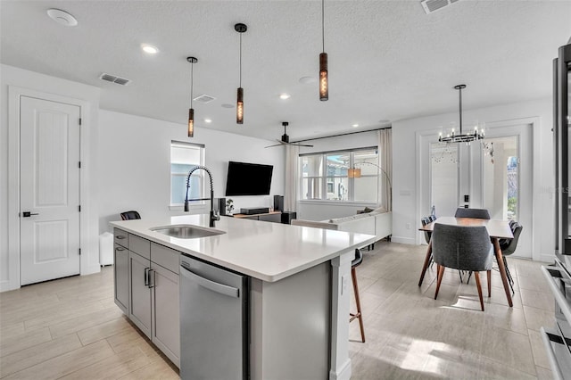 kitchen featuring visible vents, dishwasher, light countertops, gray cabinets, and a sink