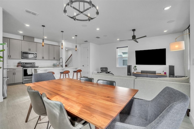 dining space with visible vents, stairway, light wood-type flooring, recessed lighting, and ceiling fan with notable chandelier