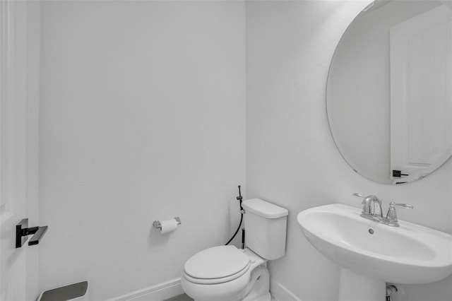 half bathroom with a sink, baseboards, and toilet