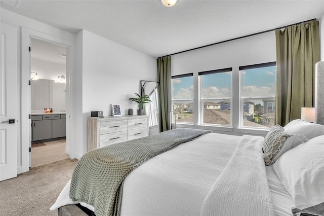 bedroom featuring light carpet, a textured ceiling, and ensuite bathroom