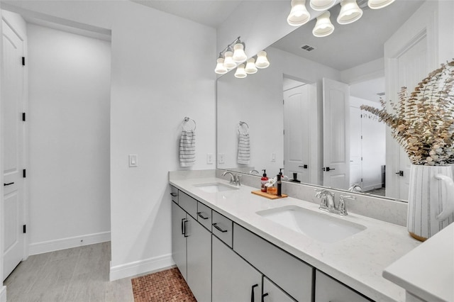 bathroom with double vanity, visible vents, baseboards, and a sink