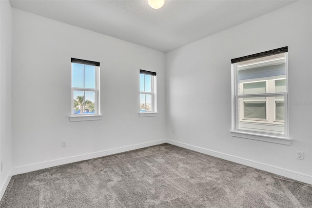 spare room featuring carpet and baseboards