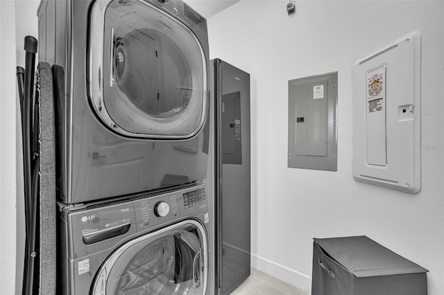 laundry area featuring laundry area, electric panel, light tile patterned flooring, and stacked washing maching and dryer